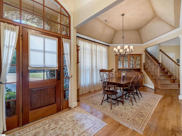 dining area with a chandelier, a tray ceiling, stairs, and wood finished floors