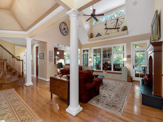 living area with a ceiling fan, light wood-style flooring, ornate columns, and stairs