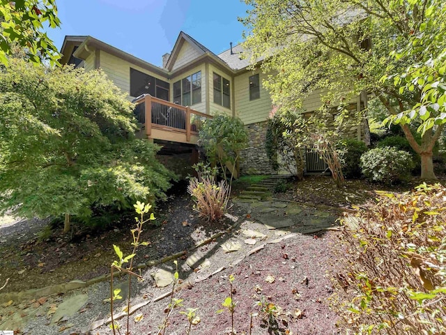 rear view of property featuring a sunroom and stone siding