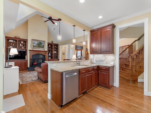 kitchen with a fireplace with raised hearth, light stone counters, a sink, open floor plan, and stainless steel dishwasher