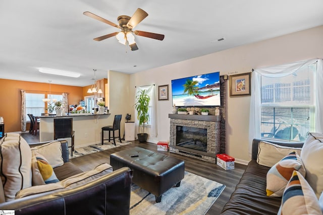 living area featuring a fireplace, wood finished floors, visible vents, a ceiling fan, and baseboards