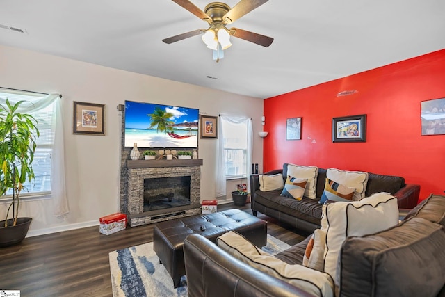 living area with ceiling fan, a fireplace, wood finished floors, visible vents, and baseboards