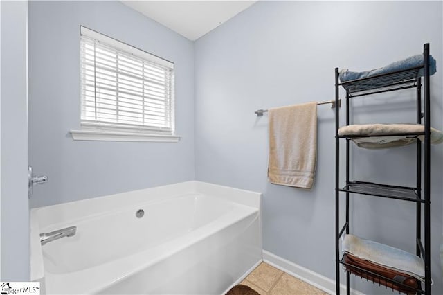 bathroom with tile patterned flooring, a bath, and baseboards