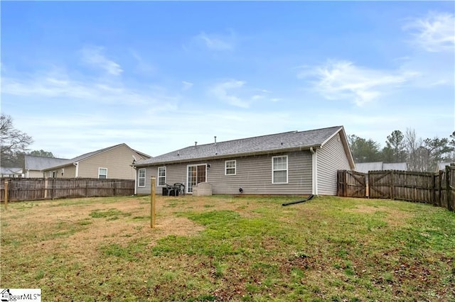 back of property with a fenced backyard and a lawn