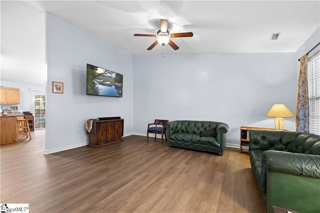 living room featuring a ceiling fan, wood finished floors, visible vents, and baseboards