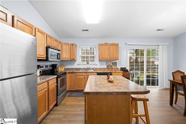 kitchen featuring appliances with stainless steel finishes, visible vents, dark wood-type flooring, and a kitchen bar