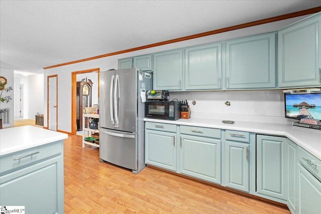 kitchen featuring blue cabinets, light wood-style flooring, black microwave, and freestanding refrigerator