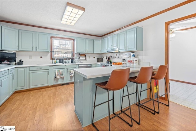 kitchen featuring ornamental molding, a sink, a peninsula, and blue cabinetry