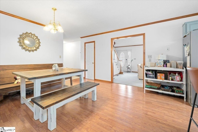 dining area with ornamental molding, baseboards, a notable chandelier, and light wood finished floors