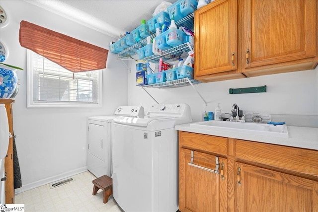 laundry area with cabinet space, visible vents, washing machine and clothes dryer, light floors, and a sink