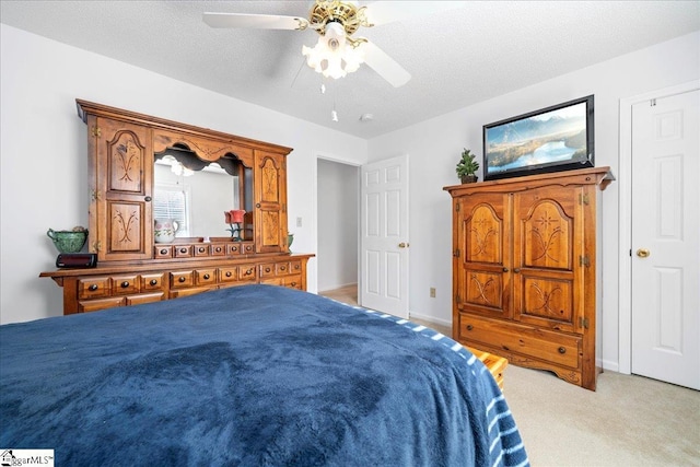 bedroom with a ceiling fan, light colored carpet, a textured ceiling, and baseboards