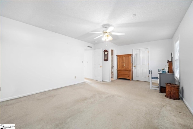 interior space featuring carpet floors, ceiling fan, a textured ceiling, and baseboards