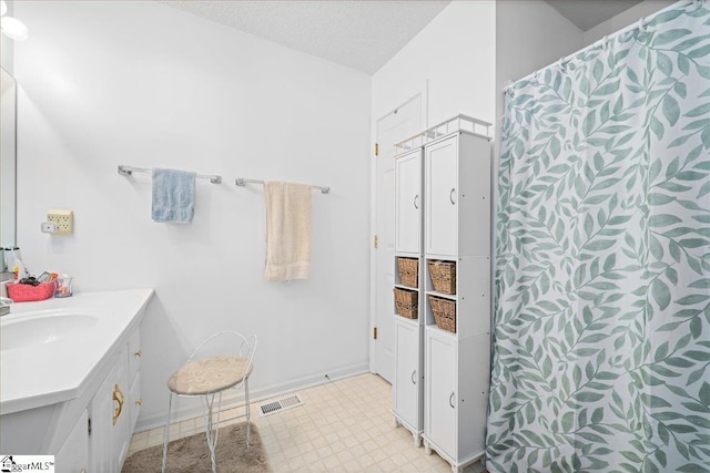 full bathroom featuring a textured ceiling, curtained shower, vanity, visible vents, and tile patterned floors