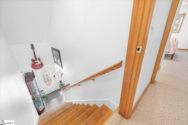 stairway featuring vaulted ceiling, carpet flooring, and baseboards