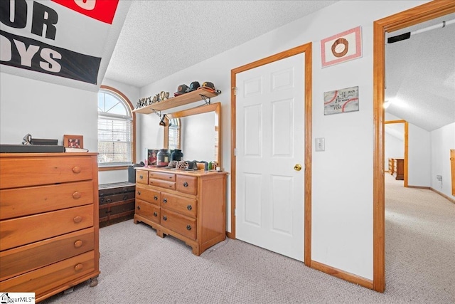 bedroom with a textured ceiling, vaulted ceiling, baseboards, and light colored carpet