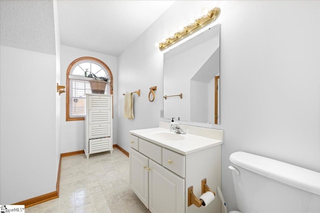 bathroom with a textured ceiling, vanity, toilet, and tile patterned floors