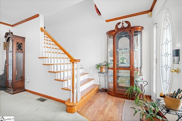 entrance foyer featuring baseboards, visible vents, stairway, ornamental molding, and wood finished floors