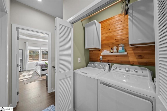 washroom with cabinet space, washer and dryer, and wood finished floors