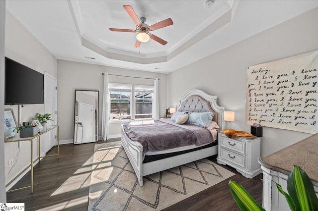 bedroom with ornamental molding, ceiling fan, wood finished floors, and a raised ceiling