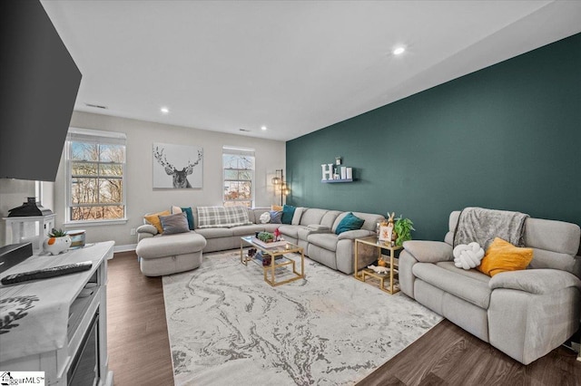 living room featuring dark wood-style floors, an accent wall, recessed lighting, and baseboards