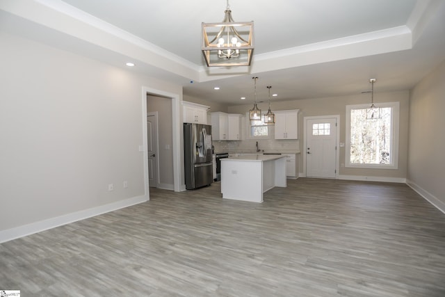 kitchen featuring a chandelier, stainless steel appliances, white cabinets, open floor plan, and baseboards