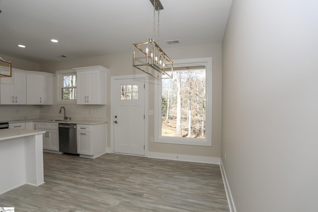 kitchen with a sink, visible vents, white cabinetry, light countertops, and dishwasher