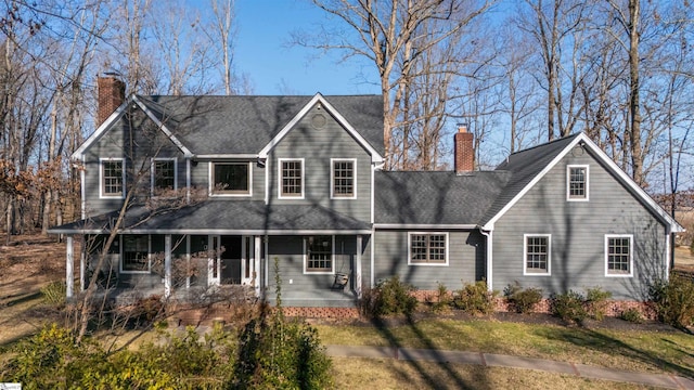 view of front of property with a shingled roof, a chimney, and a porch