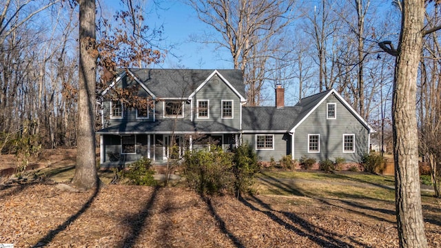 view of front of house featuring a porch, a chimney, and a front yard