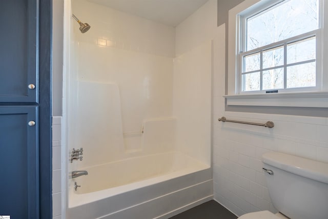 full bath featuring tile walls, a wainscoted wall, bathing tub / shower combination, and toilet