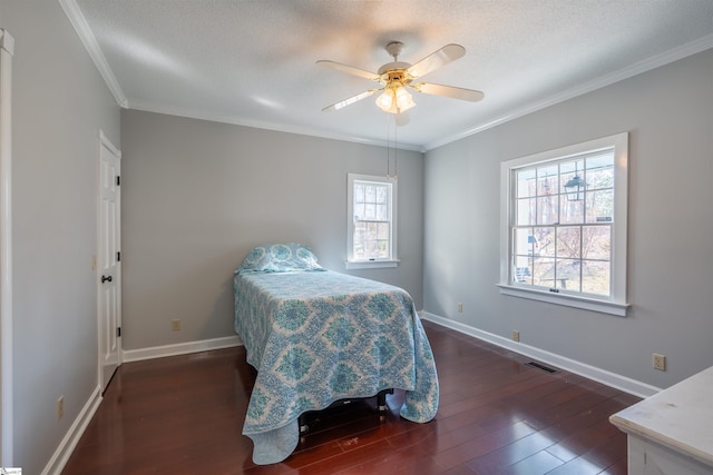 bedroom with a textured ceiling, wood finished floors, visible vents, baseboards, and crown molding