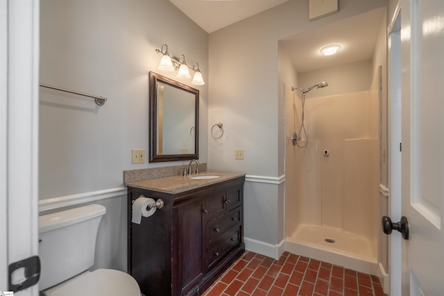 bathroom featuring baseboards, toilet, brick floor, walk in shower, and vanity