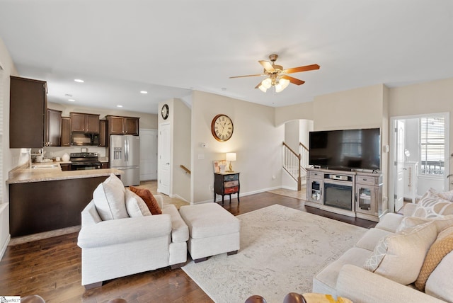 living room featuring stairway, baseboards, dark wood-type flooring, and recessed lighting