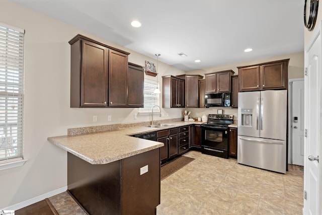 kitchen with a peninsula, light countertops, dark brown cabinets, black appliances, and a sink