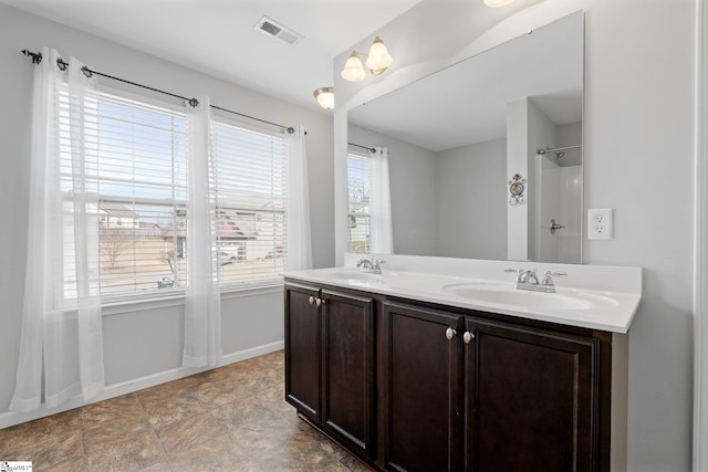 full bathroom featuring double vanity, a sink, visible vents, and baseboards