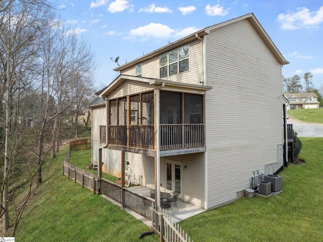 view of side of home featuring a patio, french doors, a lawn, and a sunroom