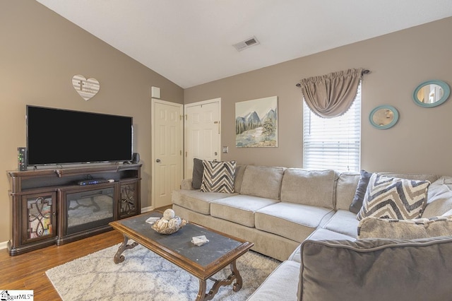 living area with lofted ceiling, wood finished floors, visible vents, and baseboards