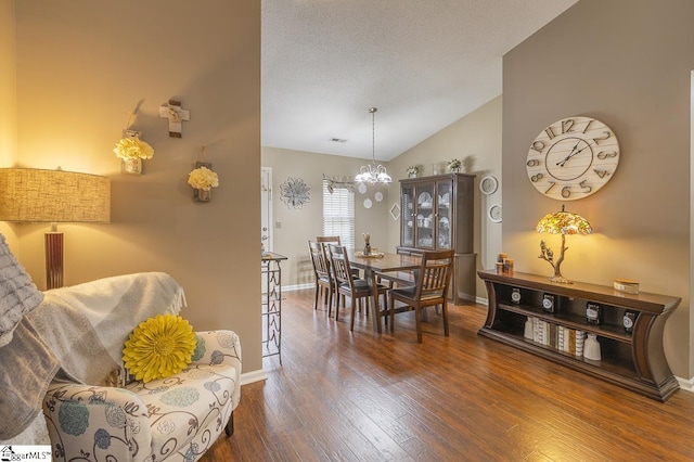 dining area featuring vaulted ceiling, a textured ceiling, baseboards, and wood finished floors