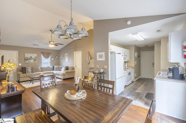 dining space featuring ceiling fan with notable chandelier, lofted ceiling, visible vents, and wood finished floors