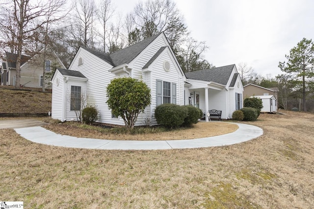 view of home's exterior featuring a shingled roof, a lawn, and an outbuilding