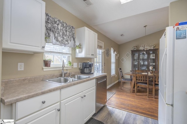 kitchen featuring a sink, white cabinets, vaulted ceiling, freestanding refrigerator, and dishwasher