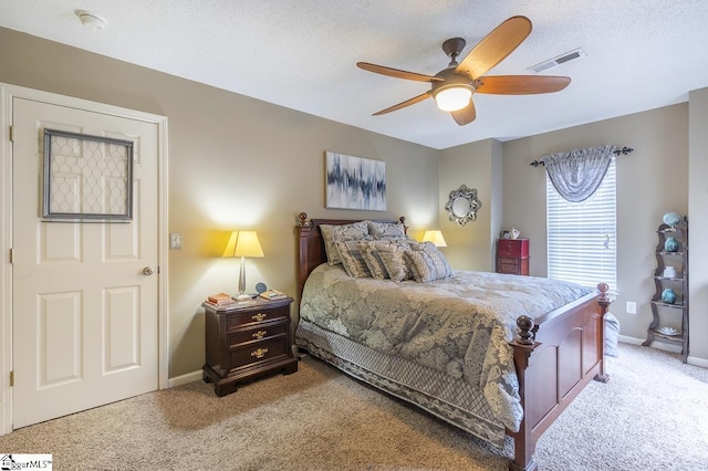 bedroom featuring light colored carpet, visible vents, and a textured ceiling