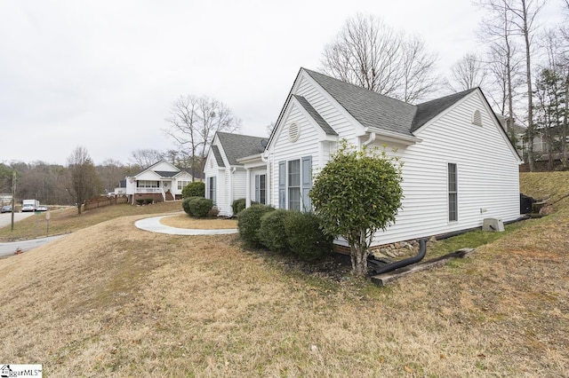 view of home's exterior with a lawn and roof with shingles