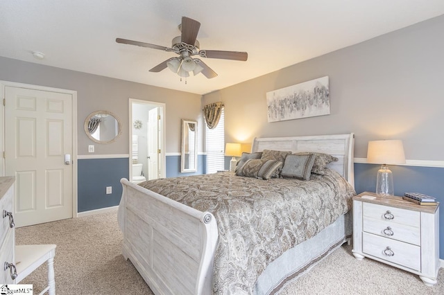 bedroom with light carpet, ensuite bath, and a ceiling fan