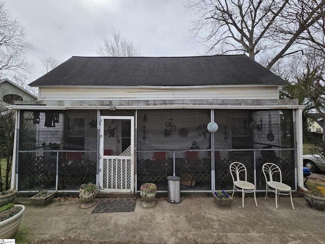 exterior space featuring a sunroom and a shingled roof