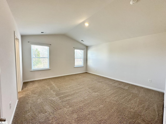 carpeted spare room featuring lofted ceiling, visible vents, and baseboards