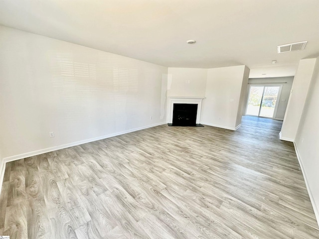 unfurnished living room with light wood-style floors, visible vents, a fireplace, and baseboards