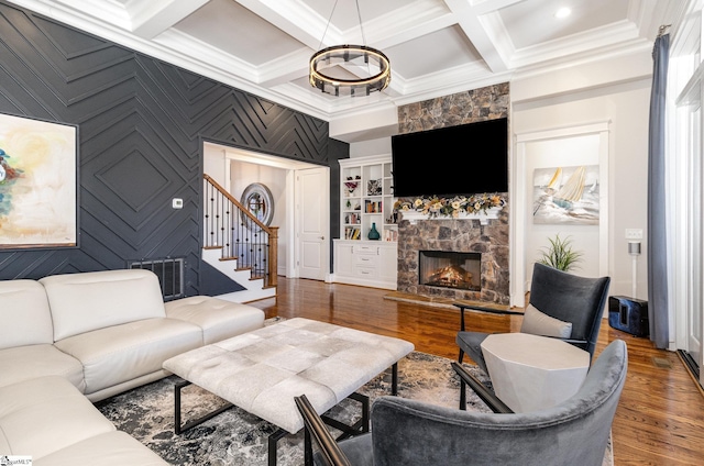 living room with coffered ceiling, visible vents, a stone fireplace, and wood finished floors