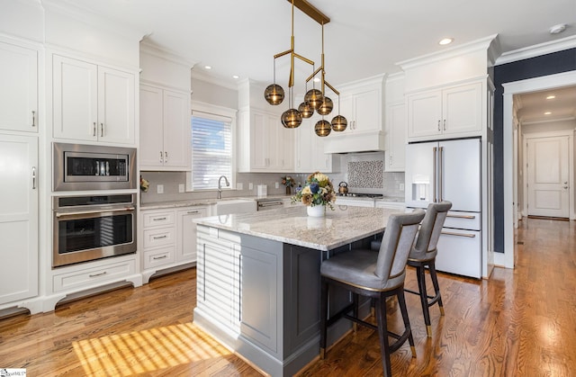 kitchen with stainless steel appliances, a sink, white cabinets, tasteful backsplash, and crown molding