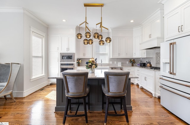 kitchen featuring white cabinetry, stainless steel appliances, decorative backsplash, and a center island