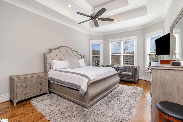 bedroom with baseboards, a tray ceiling, ornamental molding, and wood finished floors